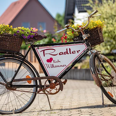 Ein altes Fahrrad, aufbereitet zu einem herzlichen "Willkommens-Schild" für Radler
