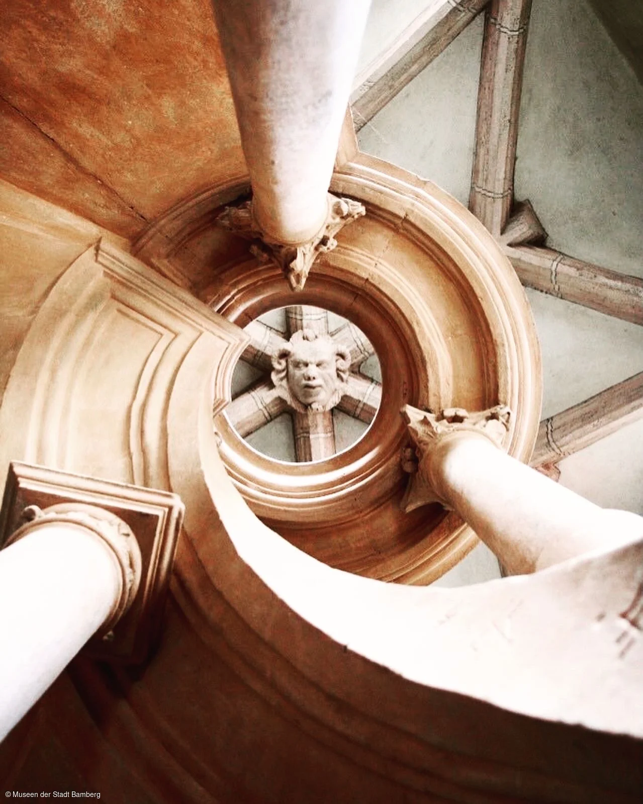 Am Ende einer steilen Wendeltreppe befindet sich ein Widderkopf aus Stein