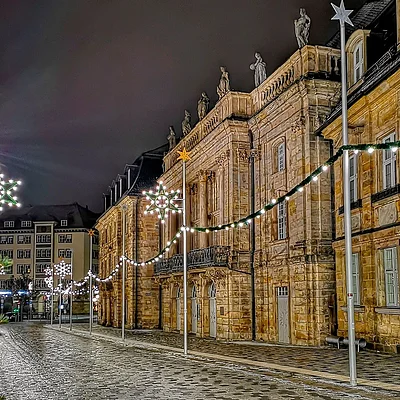 Beleuchtete Straße mit historischen Gebäuden und Weihnachtsstern-Dekoration bei Nacht.