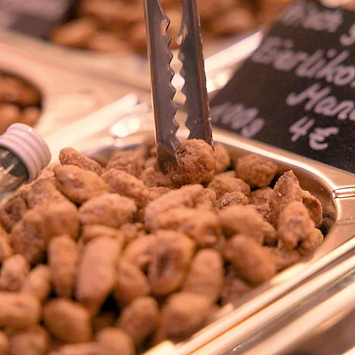 Gebrannte Erdnüsse in einer Metall-Schale mit Zange und Preisschild 4 Euro