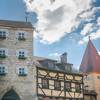 Historisches Gebäude mit Fachwerk und Torbogen, Menschen mit Fahrrädern und Café im Vordergrund.