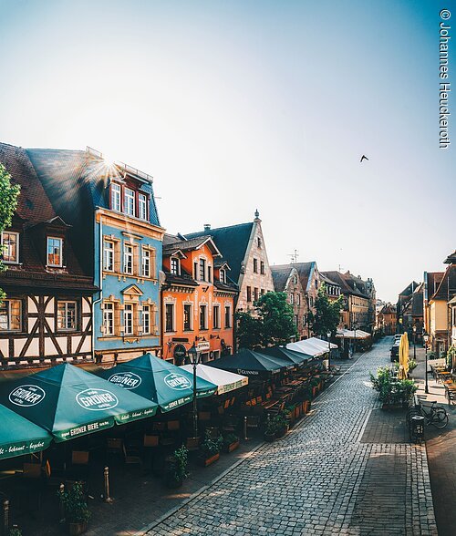 Gustavstraße (Fürth, Städteregion Nürnberg) Pflasterstraße mit Außengastronomie und bunten historischen Häusern bei Sonnenlicht am Morgen