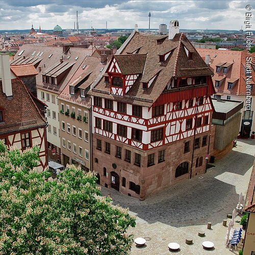 Albrecht-Dürer-Haus (Nürnberg, Städteregion Nürnberg) Historisches Fachwerkhaus mit rotem Dach in einer gepflasterten Altstadtstraße, umgeben von weiteren Gebäuden.