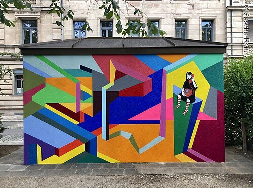 Bunte geometrische Wandmalerei mit einer sitzenden Figur, die ein Telefon hält, an einem Gebäude.