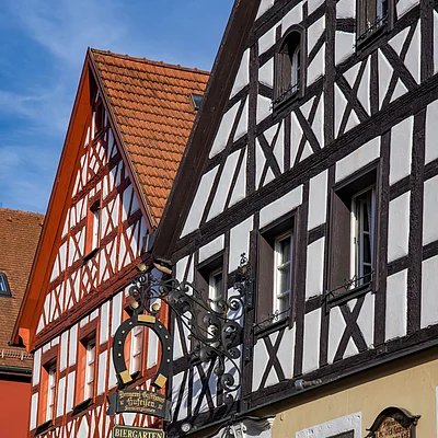 Fachwerkhäuser mit rotbraunen Dächern und einem Schild an der Hauswand.