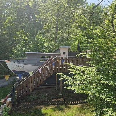 Haus in Form eines Bootes mit dem Namen Moby Dick, umgeben von Bäumen und einer Holztreppe mit Wimpelkette